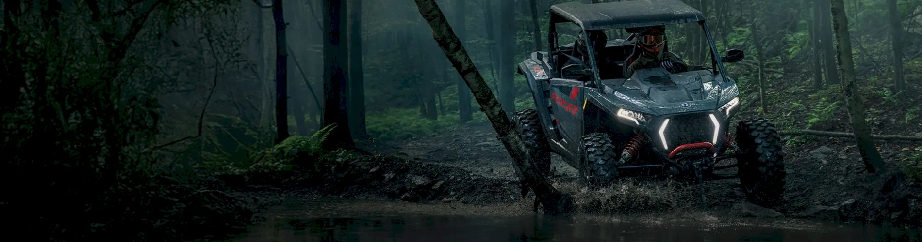 Hero banner of Polaris RZR driving through mud in dark forest